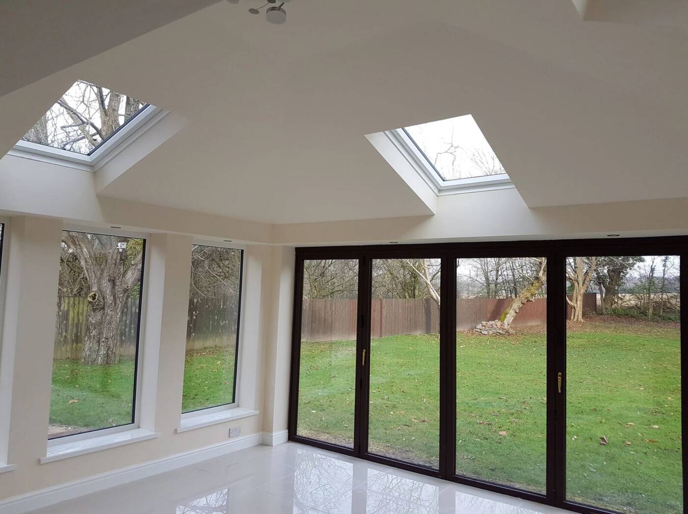 L-shaped conservatory interior in Devon with twin skylights and bi-fold doors